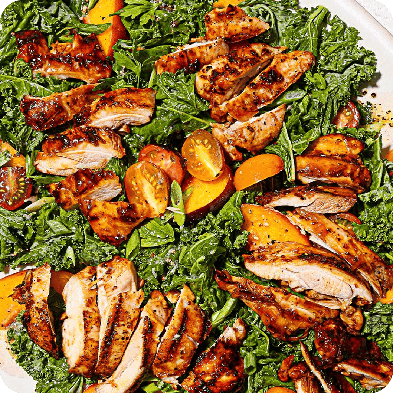 Grilled chicken slices with kale, cherry tomatoes, and peaches — buy free range chicken online for fresh, healthy salads.