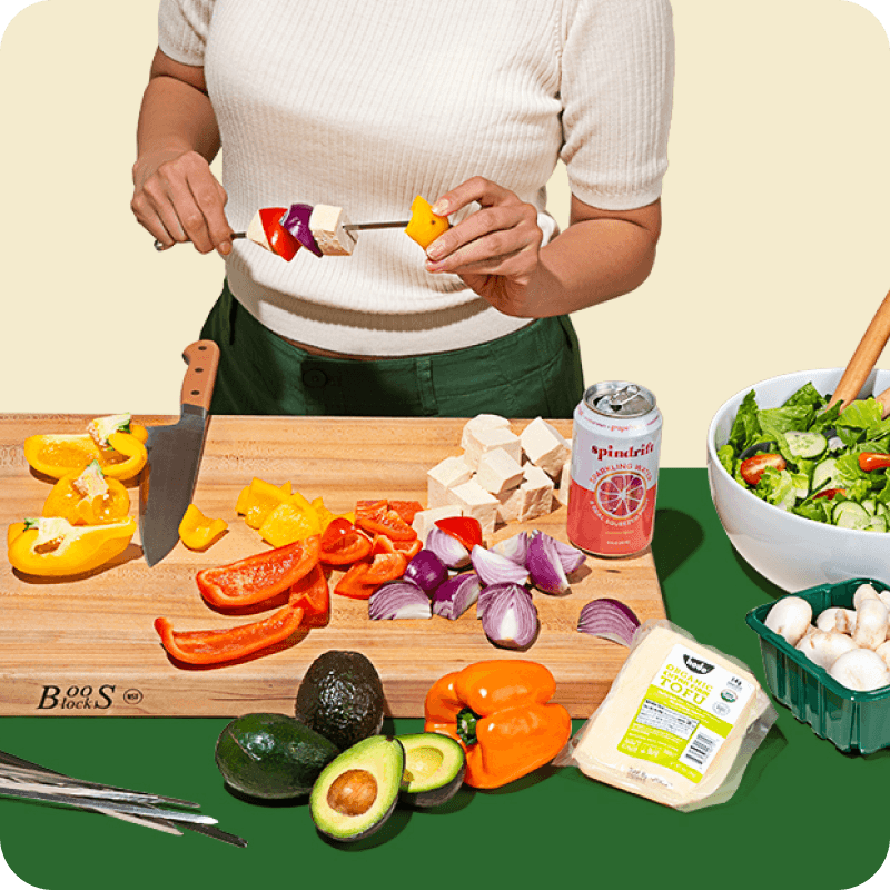 Image of a person standing in front of a cutting board of produce