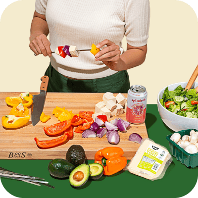 Image of a person standing in front of a cutting board of produce