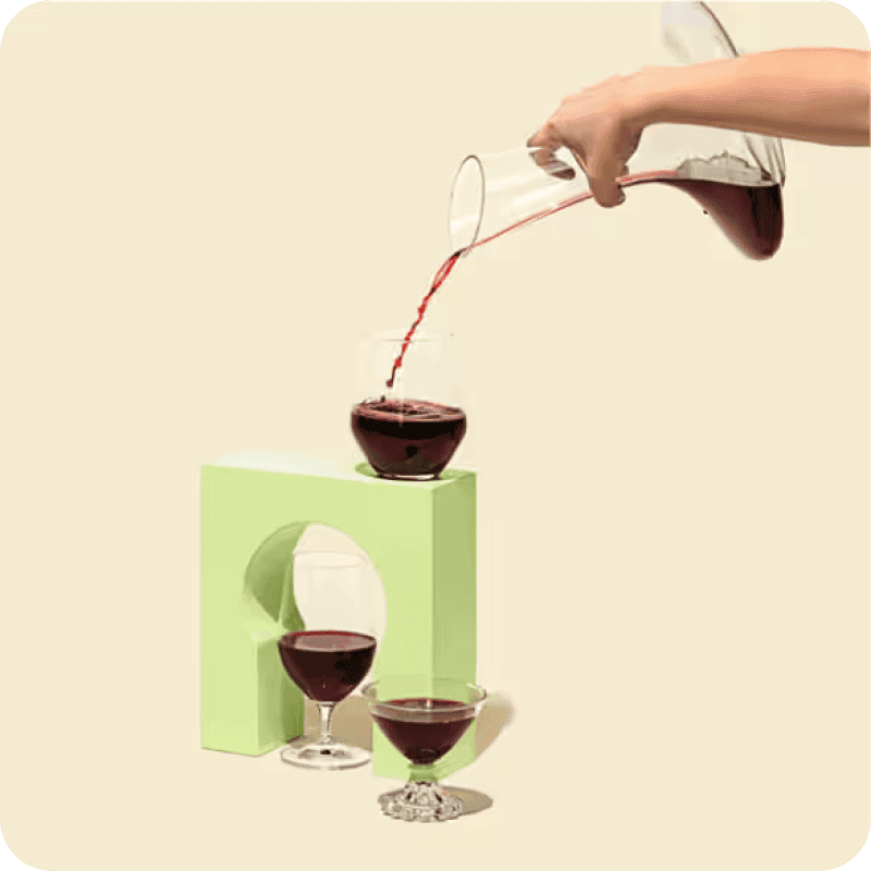 Person's hand pouring red wine into a glass