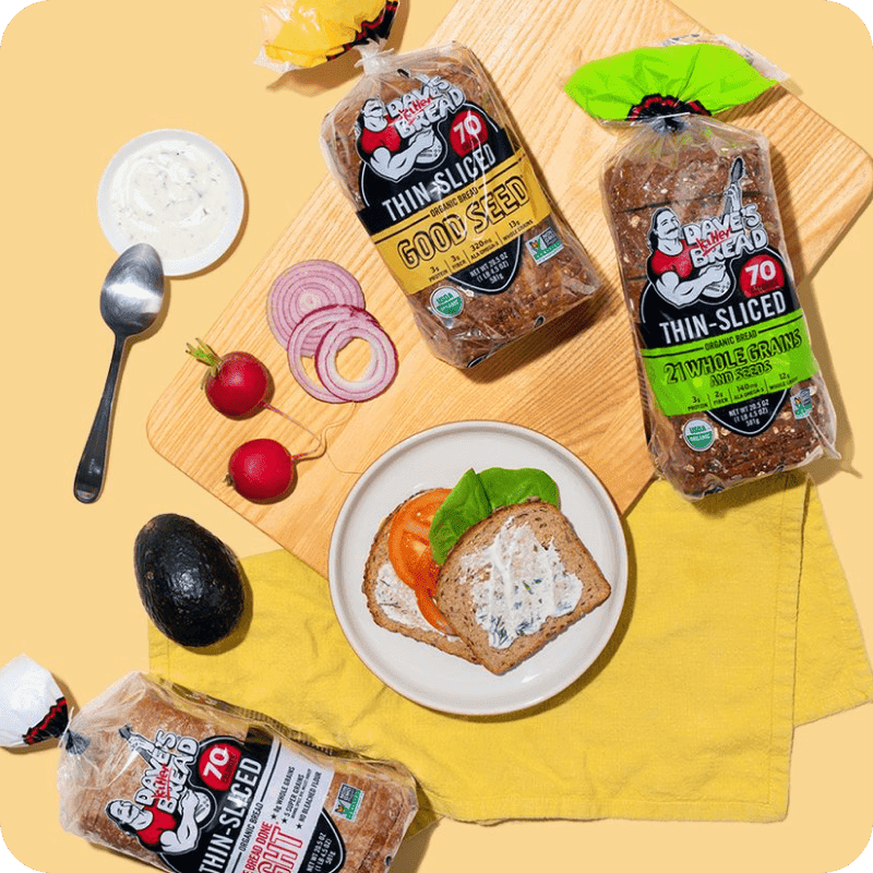 Dave's Killer Bread Thin-Sliced Good Seed and 21 Whole Grains loaves with open-faced sandwich, available for baked goods delivery