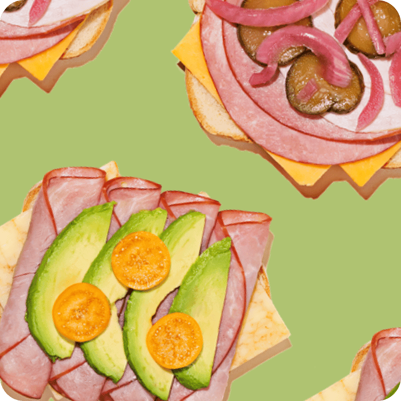 Open-faced sliced ham delivery sandwich builds topped with avocado and tomato or pickled onions, mushrooms, and cheddar cheese.