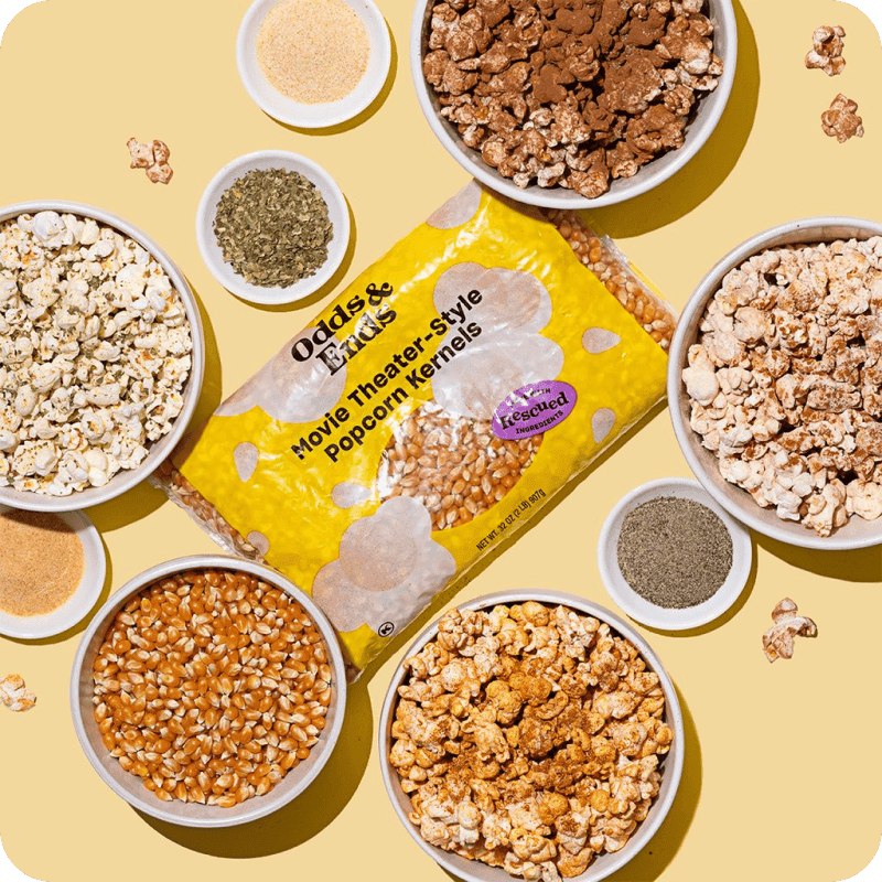 Odds & Ends Movie Theater-Style Popcorn Kernels bag surrounded by bowls of popped popcorn and spices, available for gourmet popcorn delivery.