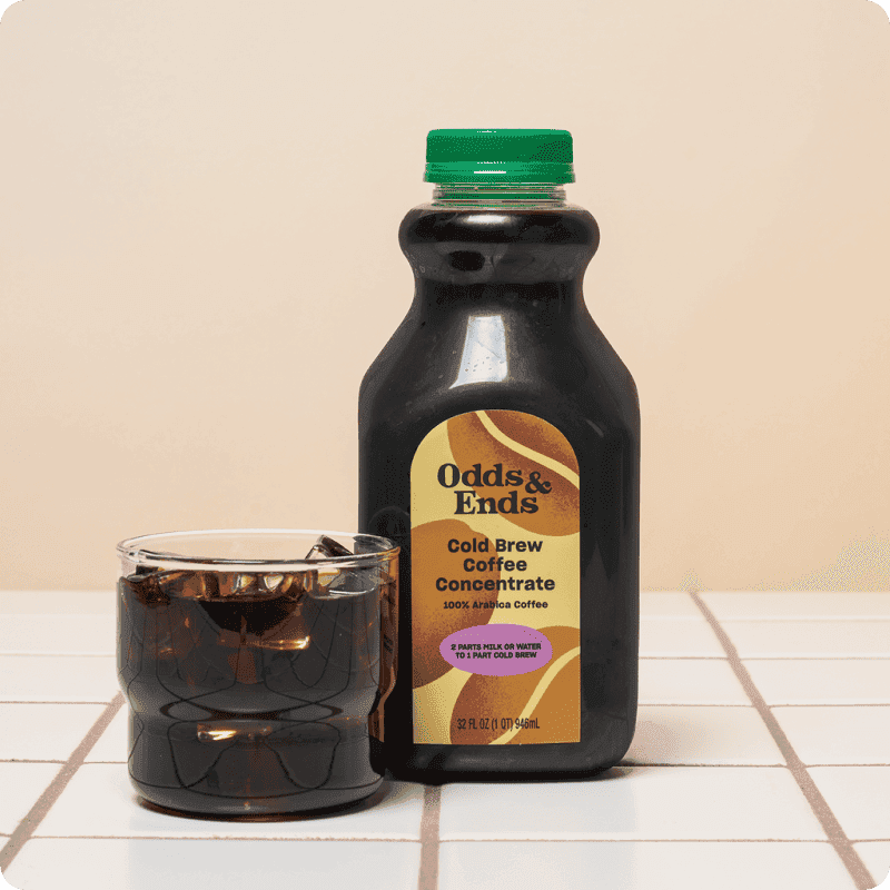 Coffee delivery pick: Odds & Ends Cold Brew Coffee Concentrate bottle with a glass of iced coffee on a tiled counter.