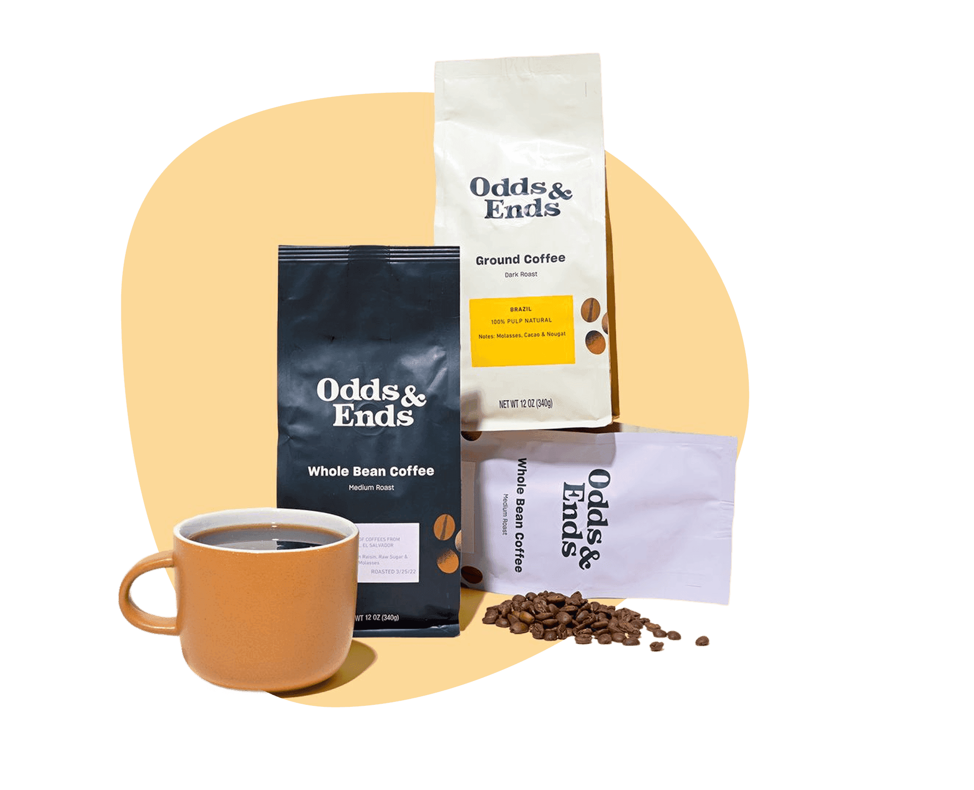 Order coffee beans online: Odds & Ends whole bean and ground coffee bags with beans scattered beside a coffee mug. 