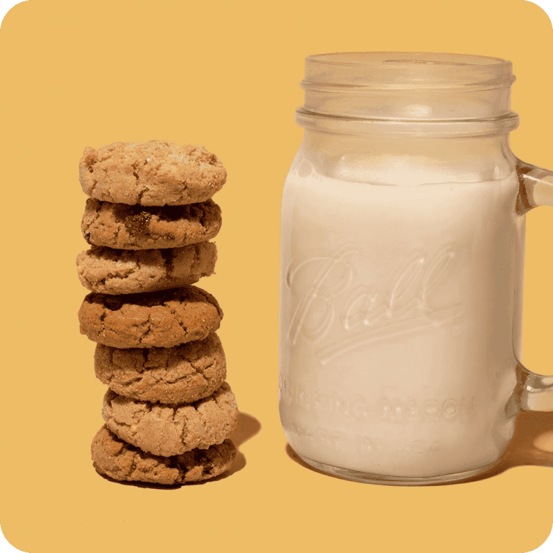 Stack of cookies next to a mason jar of organic almond milk, perfect for dairy-free almond milk delivery at home.